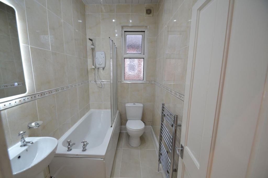 Bright, well-maintained tiled bathroom with a b...