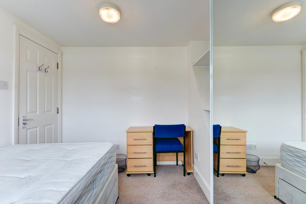 A simple, tidy bedroom featuring a mattress, wi...