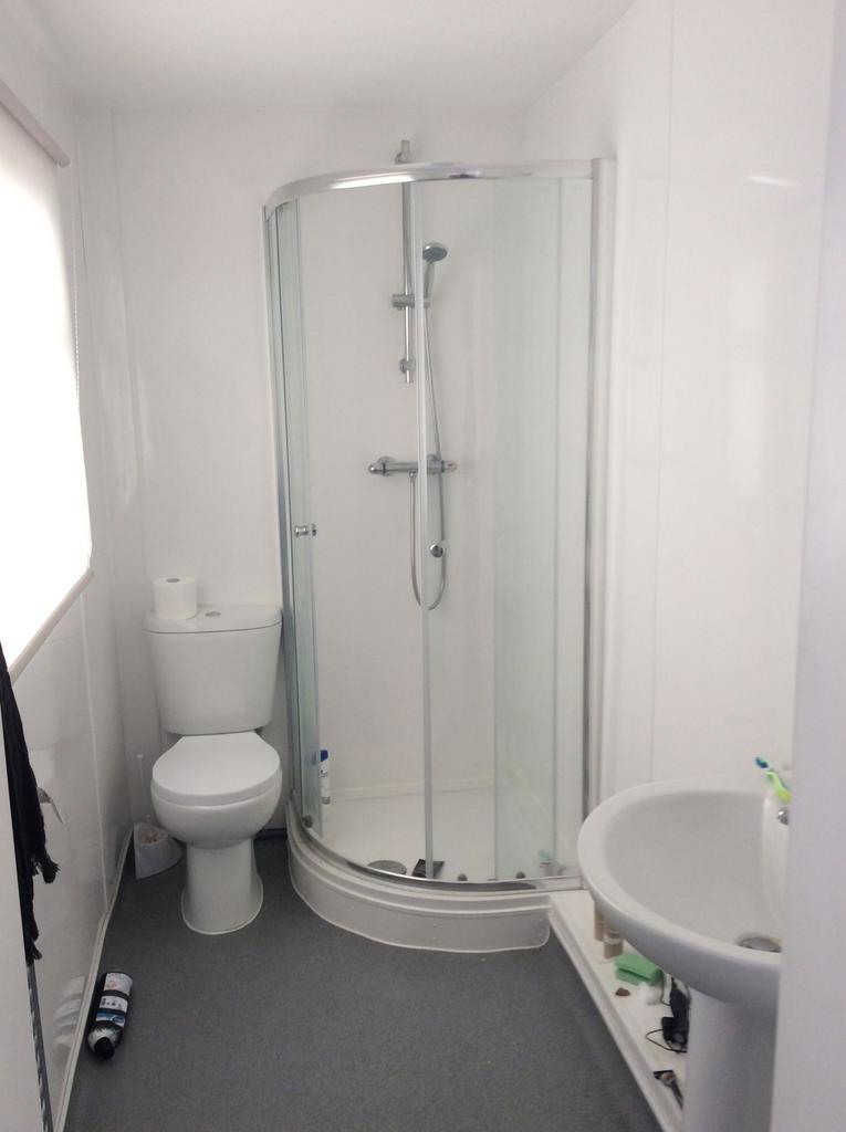 Bright, modern bathroom with a corner glass sho...