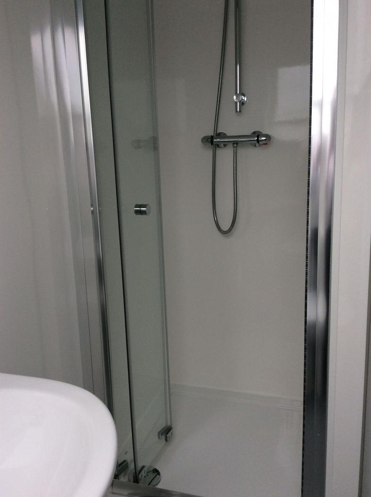 Compact modern bathroom with a glass-enclosed s...