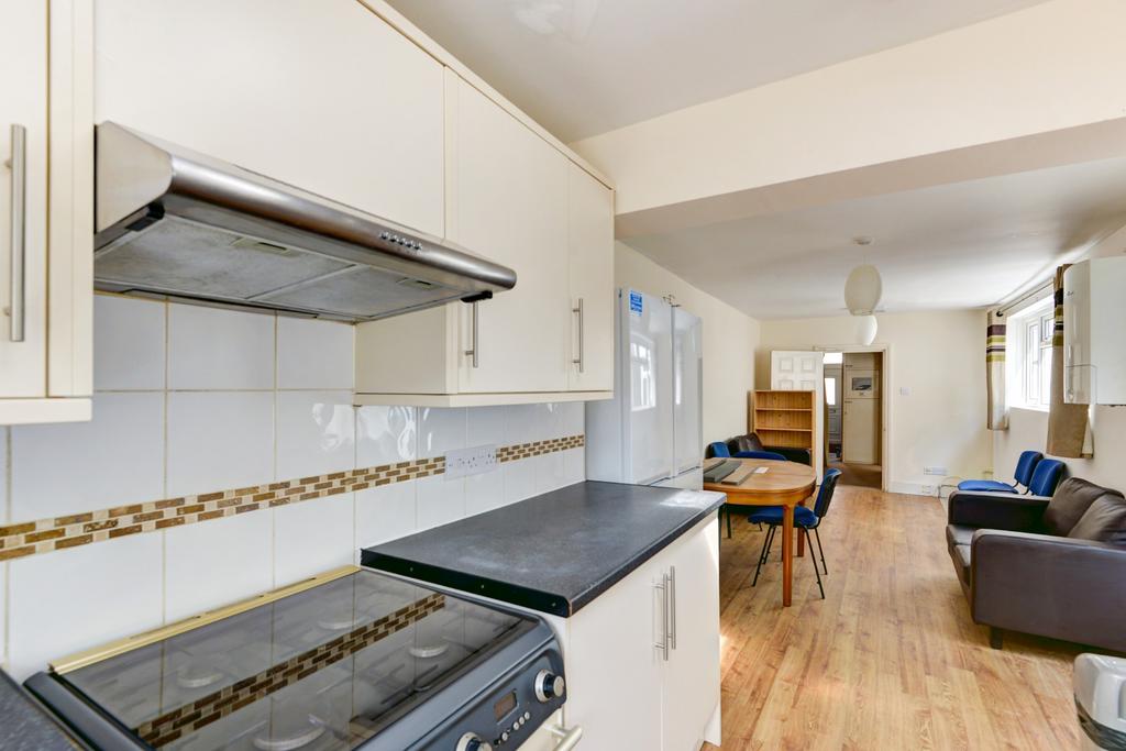 Bright open-plan kitchen with white cabinets, m...