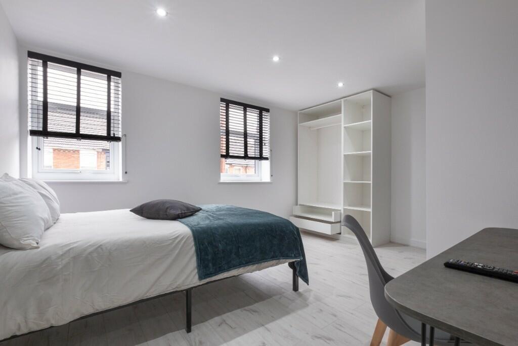 A bright and tidy bedroom featuring a large bed...