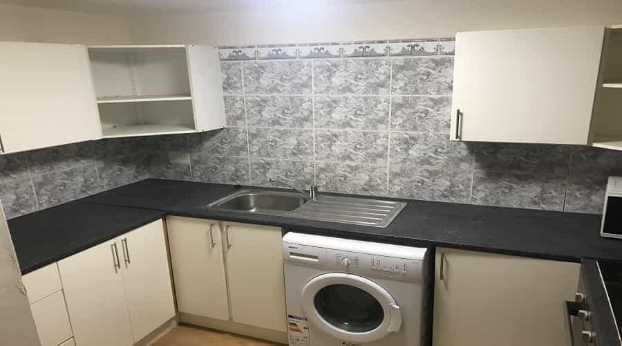 A compact, modern kitchen with white cabinets, ...