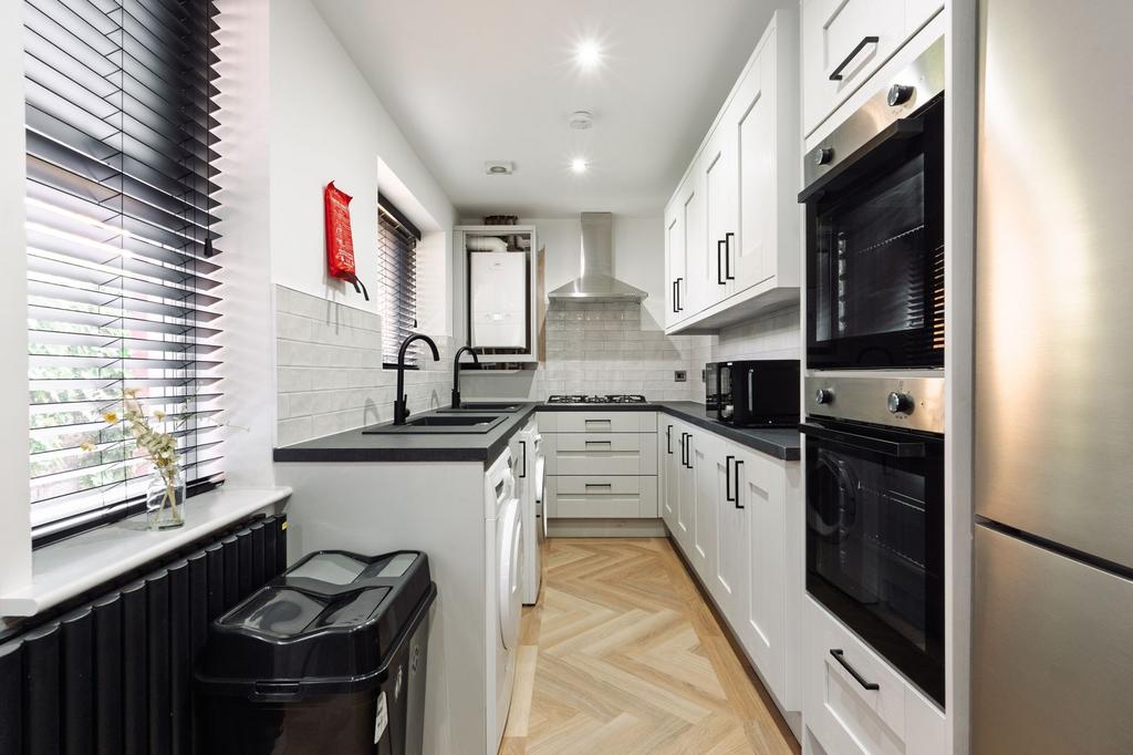 Contemporary galley kitchen with white cabinetr...