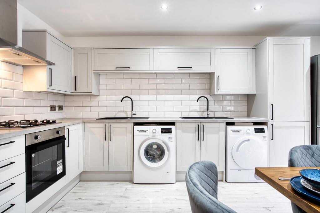 Bright and modern kitchen featuring white cabin...