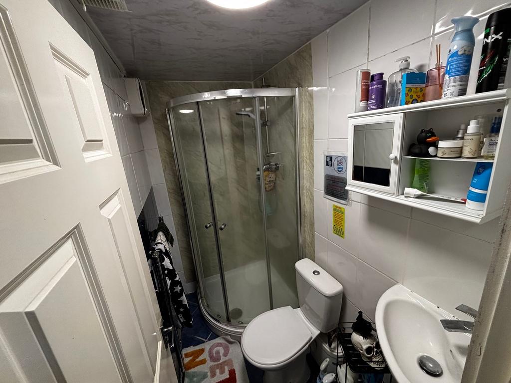 Compact tiled bathroom with a corner glass show...