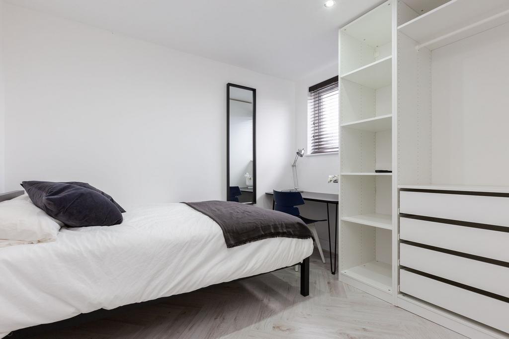 A bright, minimalist double bedroom featuring a...