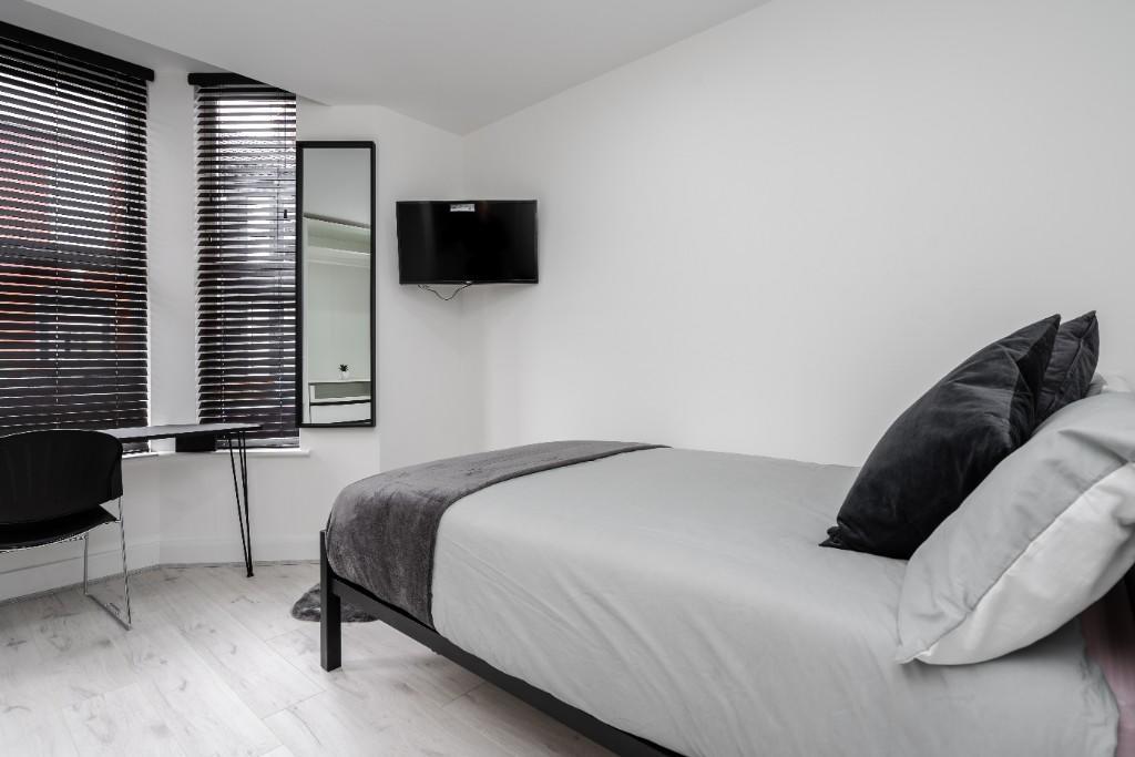 A bright and clean single bedroom featuring a n...