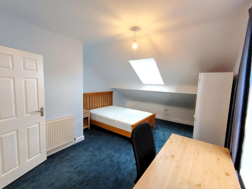 Bright attic double bedroom with a wooden bed f...