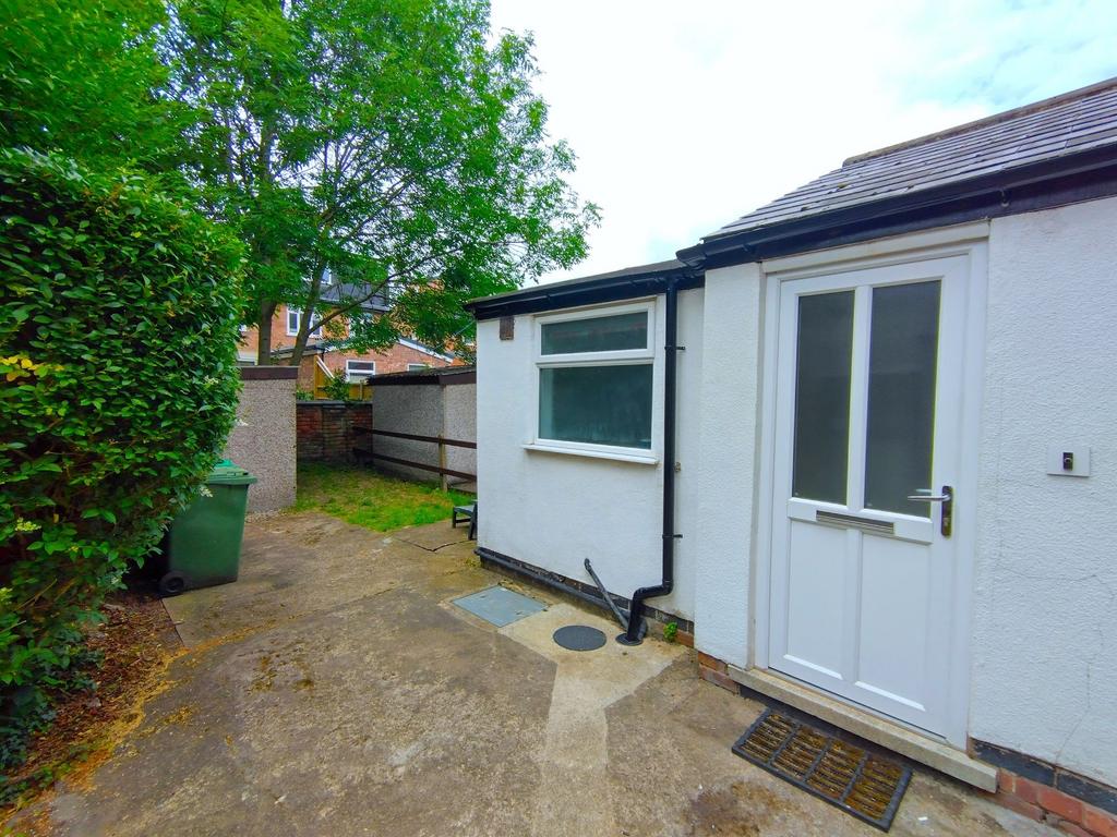 Neat paved rear yard with a white back door, fe...