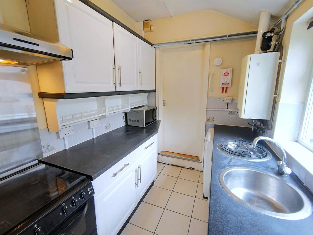 Bright galley kitchen with white cabinets, blac...