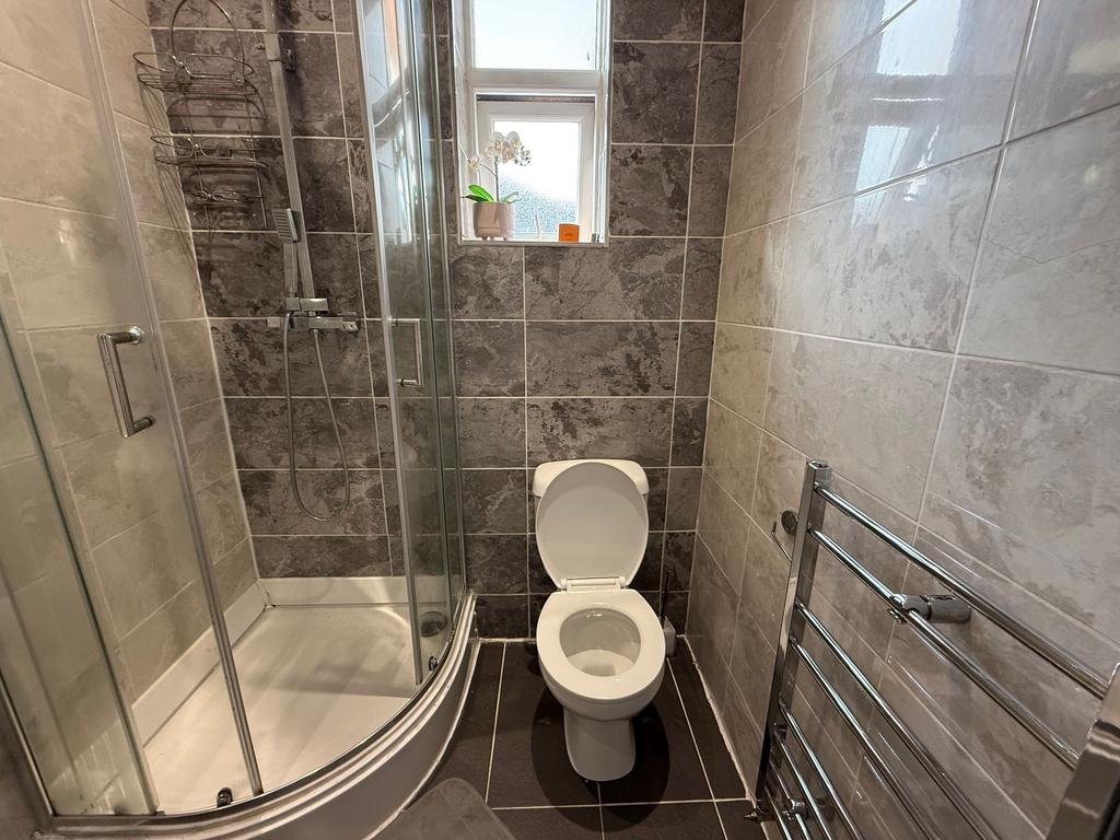 Modern tiled bathroom with a curved glass showe...