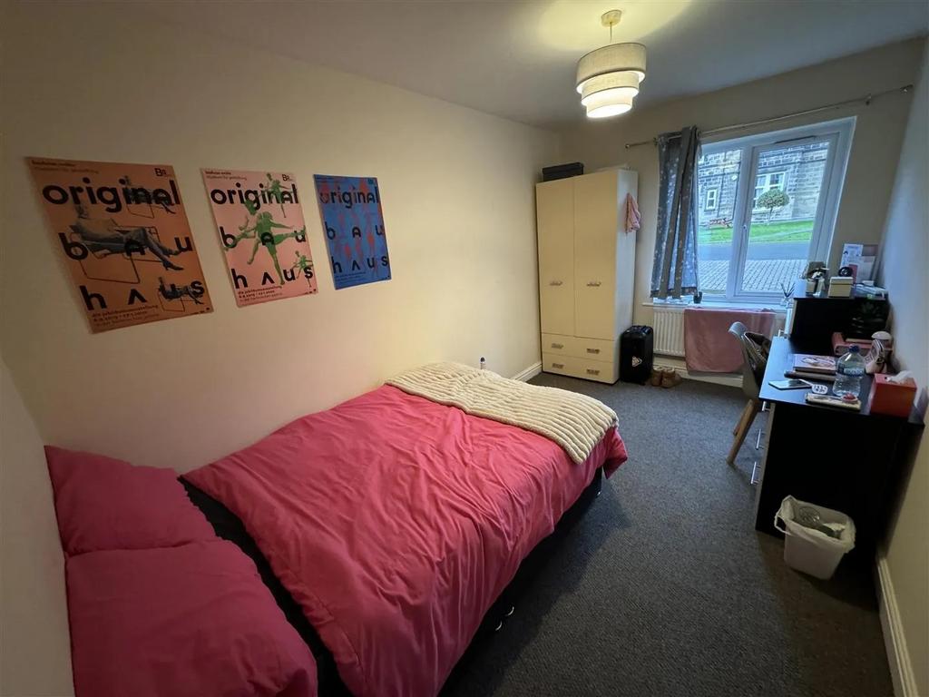 A cozy bedroom featuring a pink bedspread, a wa...