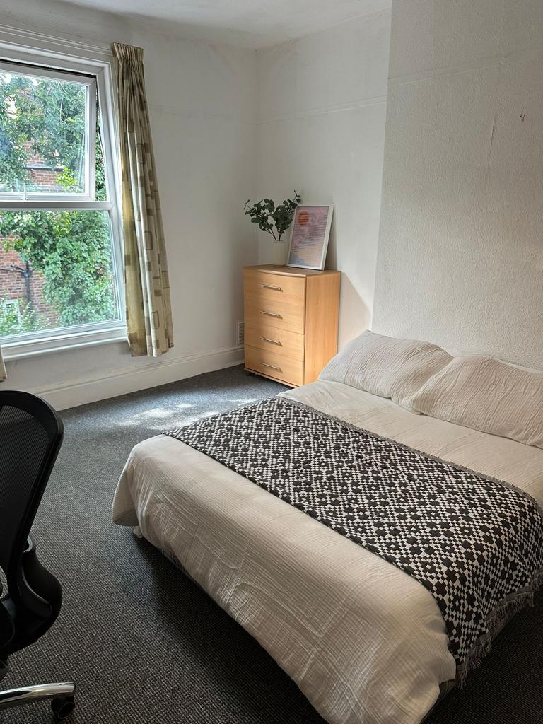 A cozy bedroom with a large window admitting na...