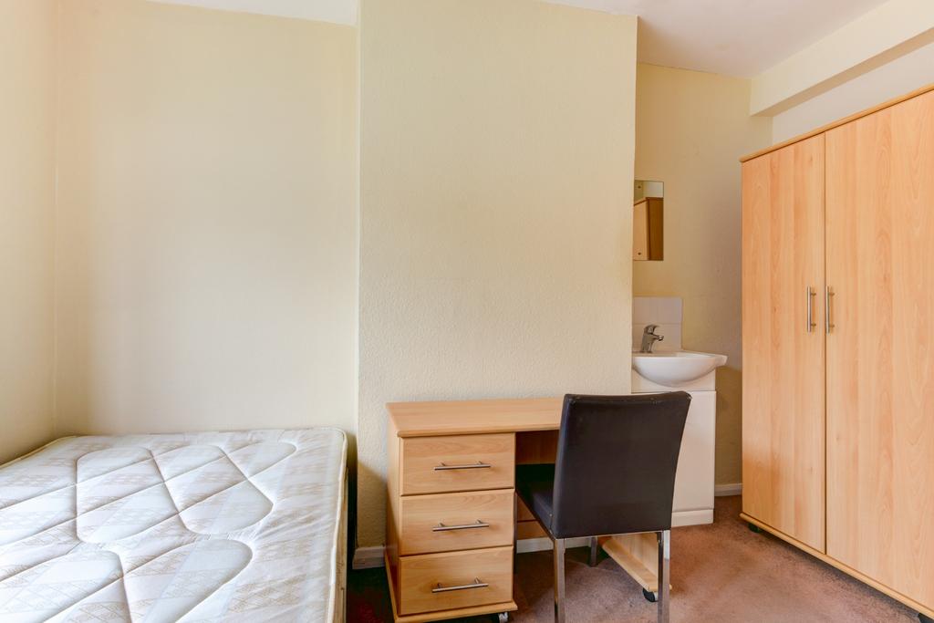 A cozy student bedroom featuring a bed, a woode...