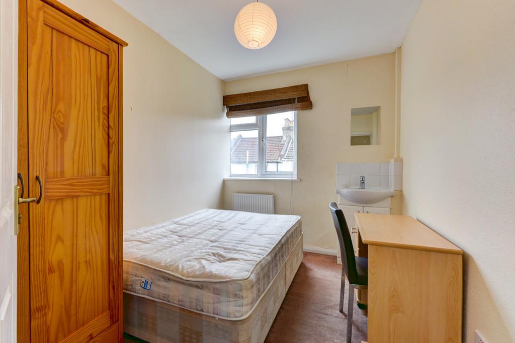 A cozy single bedroom featuring a bed, a wooden...
