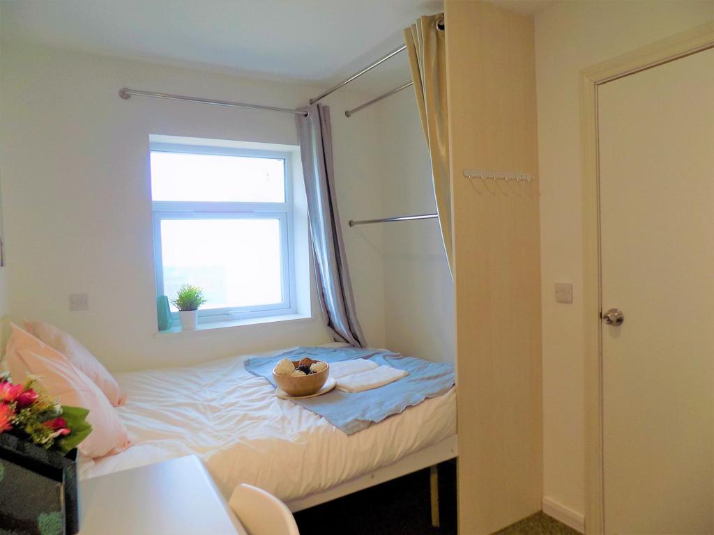A cozy, bright single bedroom featuring a neatl...
