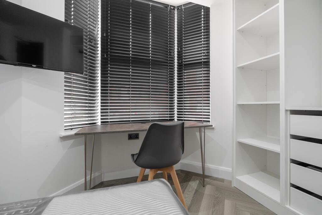 A well-kept bedroom featuring a desk area with ...