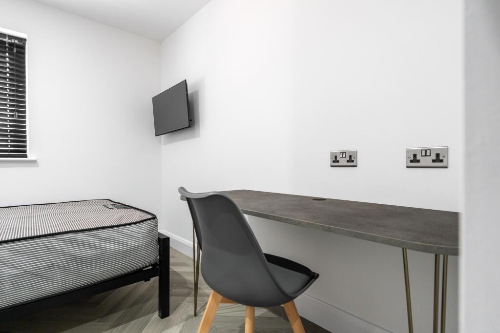 A neat and minimalistic bedroom featuring a sin...