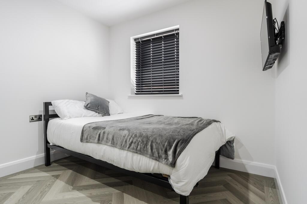 A neat and minimalist bedroom featuring a comfo...