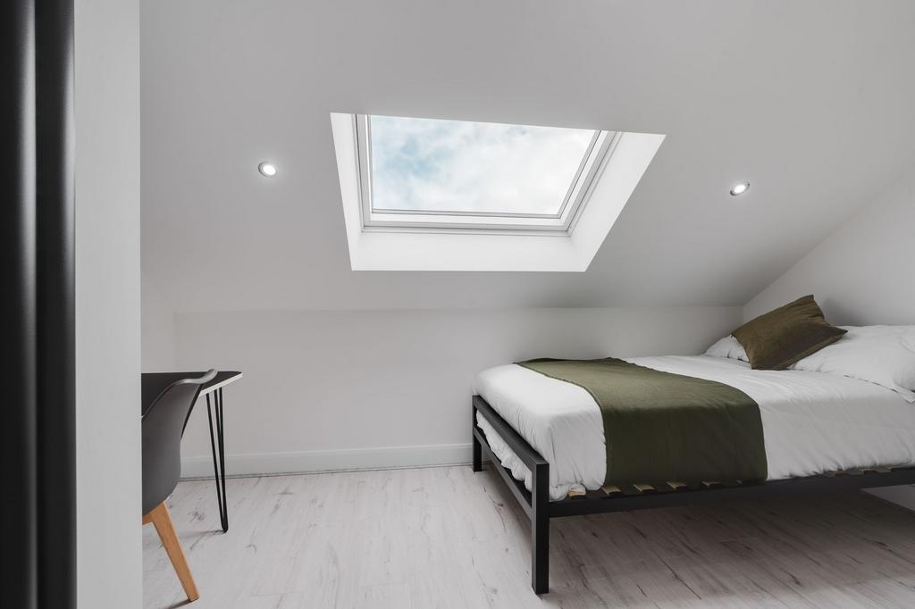 A bright and minimalist bedroom with a large sk...