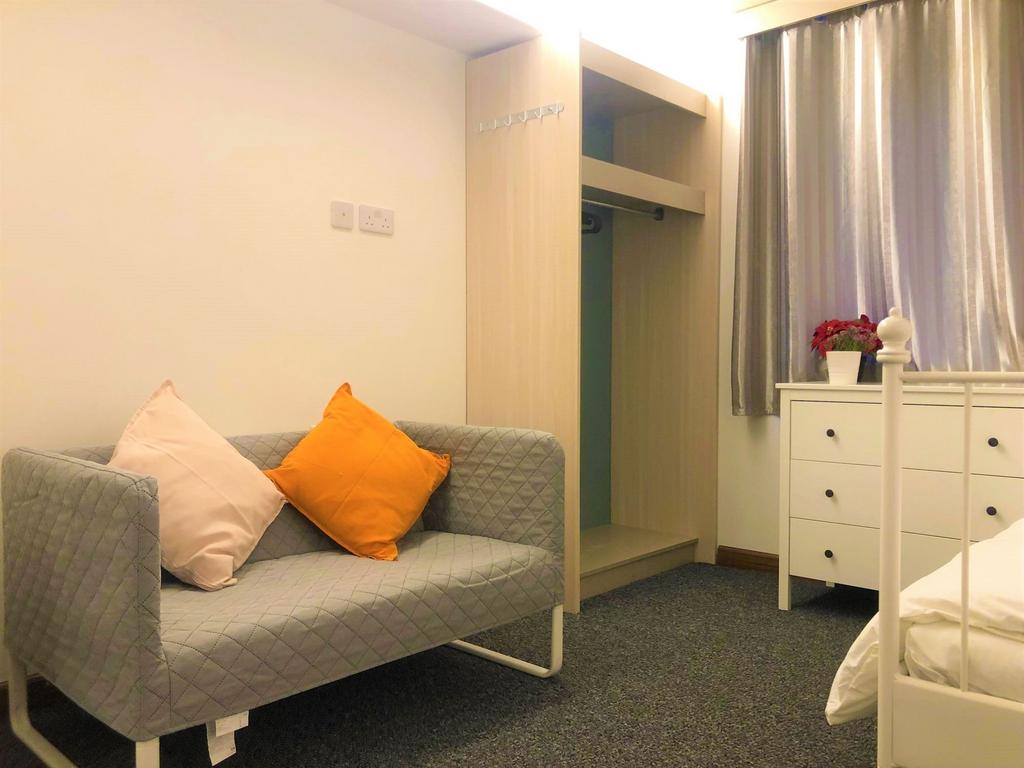 A cozy single bedroom featuring a neat grey sof...