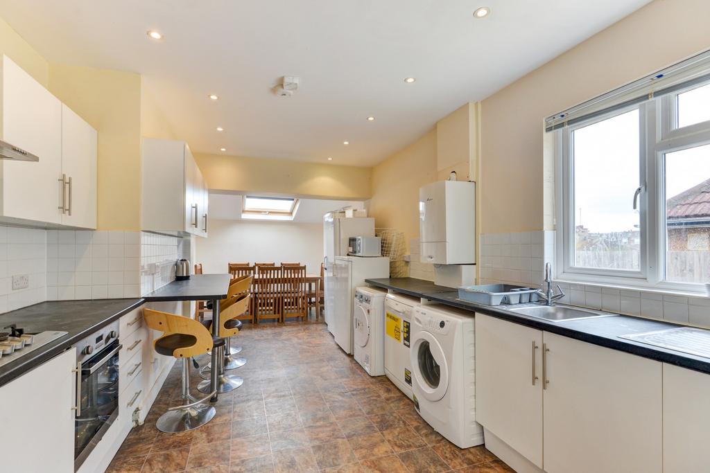 Bright, modern galley kitchen with white cabine...