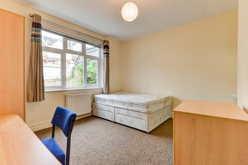 A bright, tidy student bedroom with a large win...