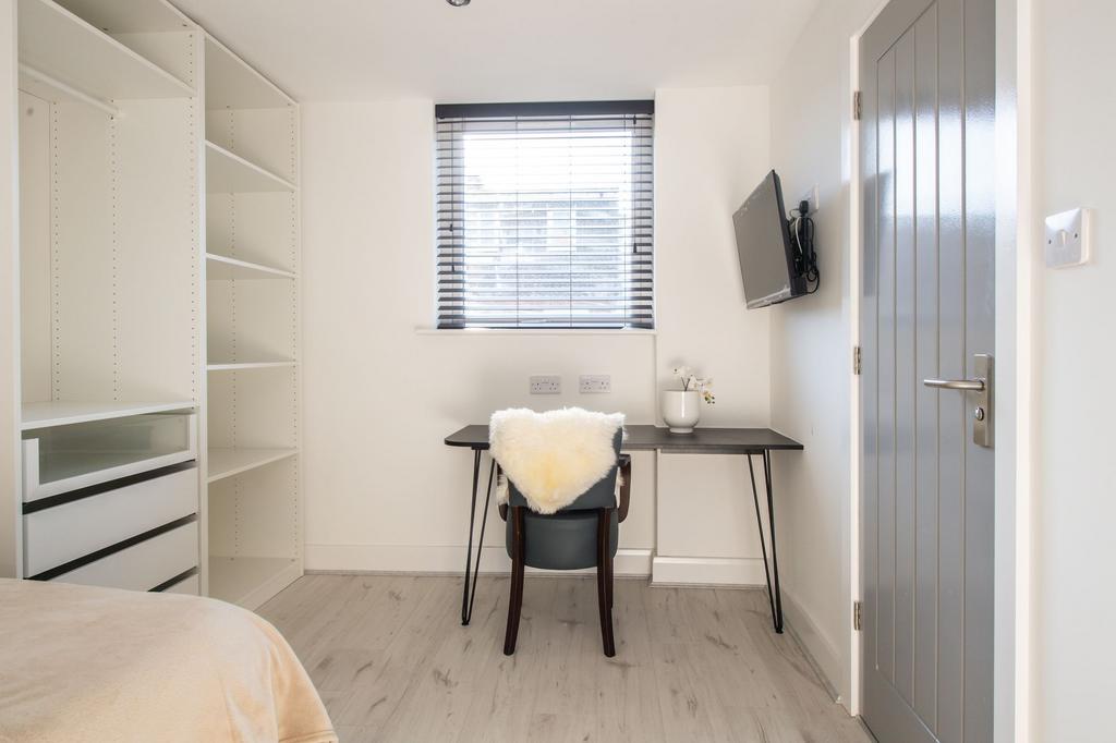 Bright and modern bedroom featuring a desk with...