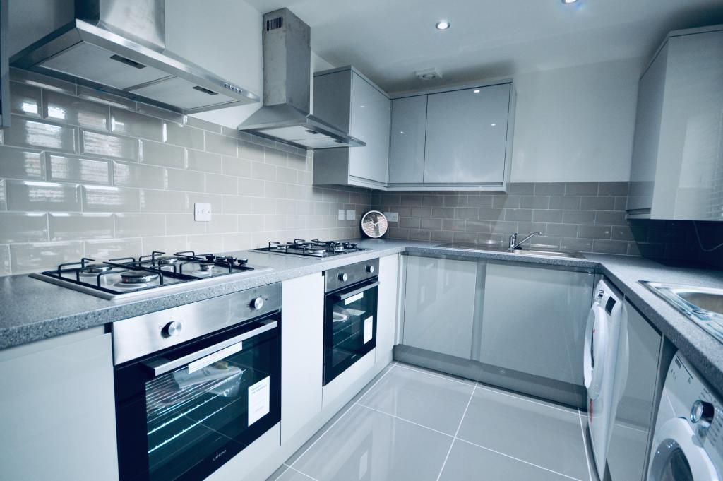 Modern fitted kitchen with matching grey cabine...