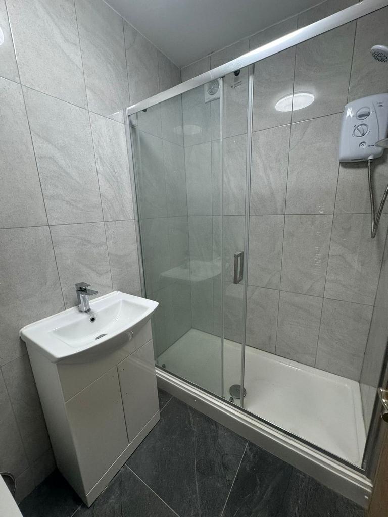 Modern tiled bathroom with a glass-enclosed sho...