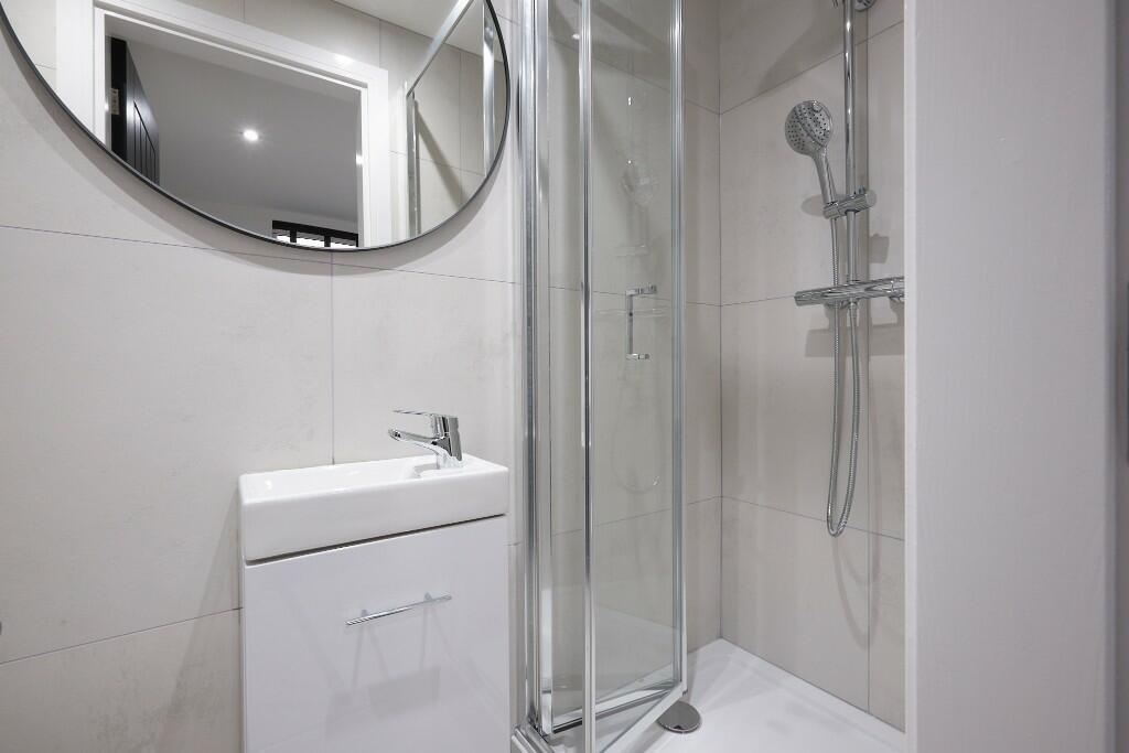 Bright, modern bathroom with a glass-enclosed s...