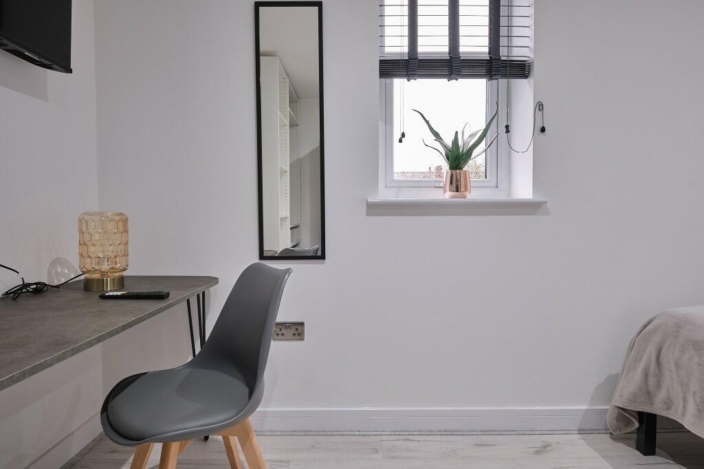 Bright, neatly arranged bedroom corner with a m...