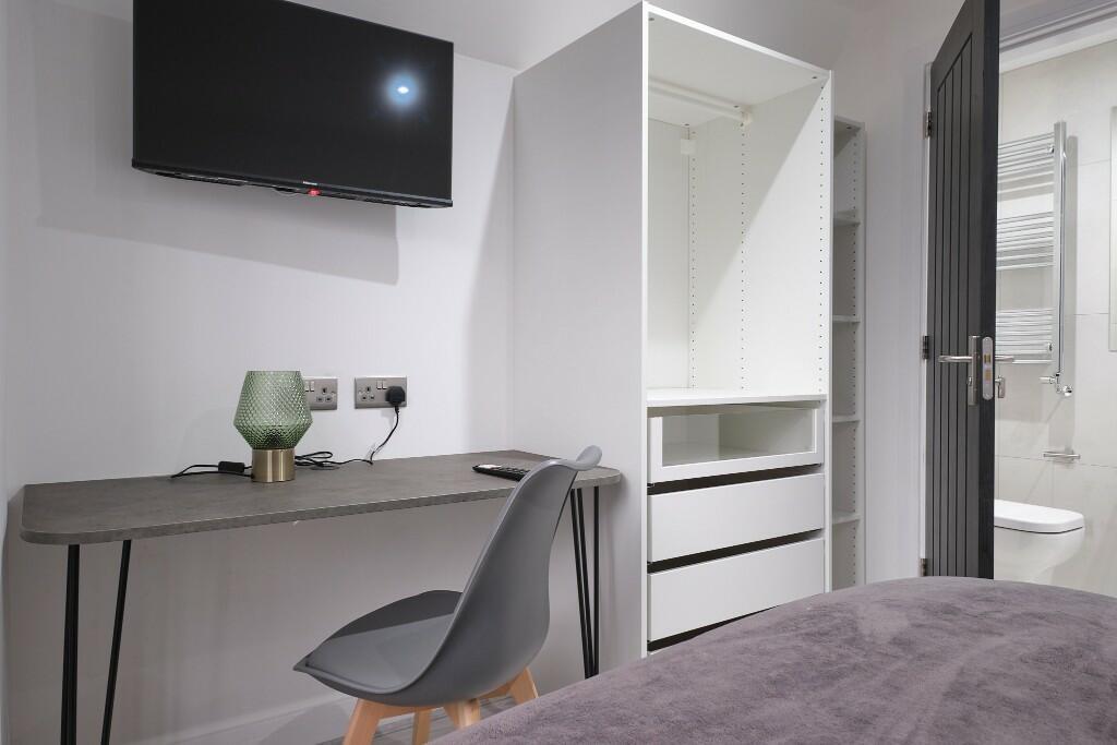 Modern single bedroom with a tidy desk area, wa...
