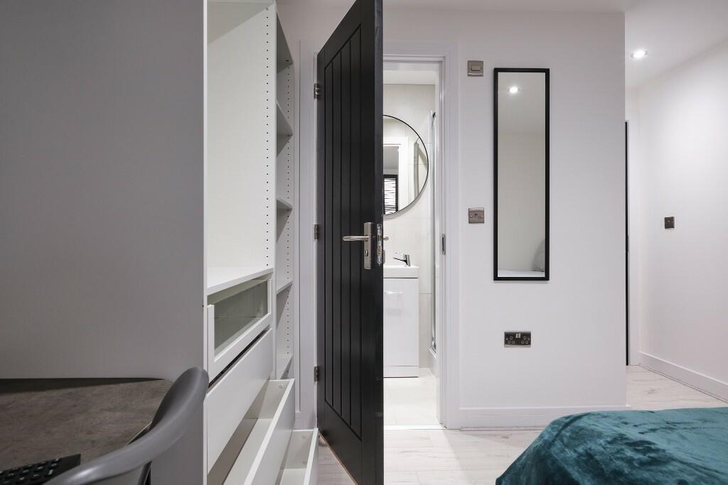 Bright, modern bedroom with a sleek black door,...