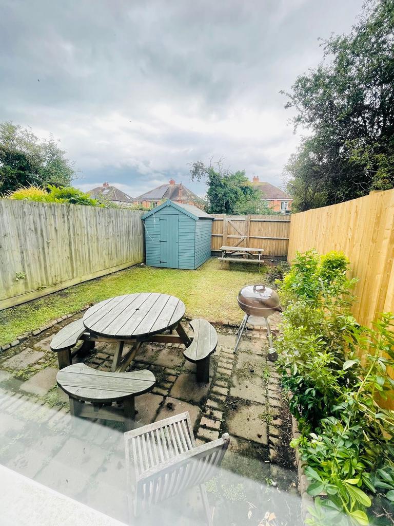 Enclosed rear garden with a painted storage she...