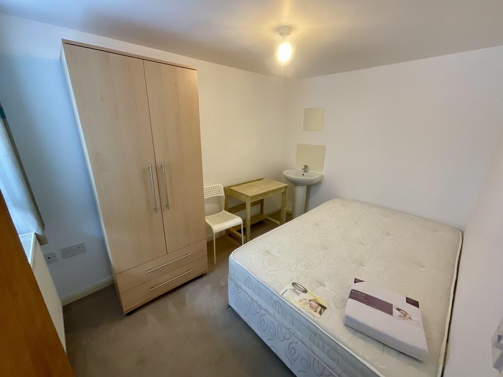 A bright and tidy bedroom featuring a bed, a wa...