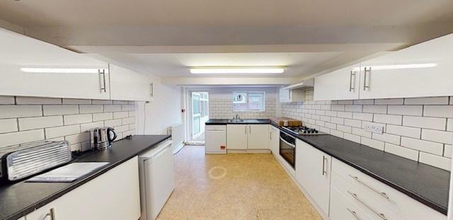 Bright modern galley kitchen with white cabinet...