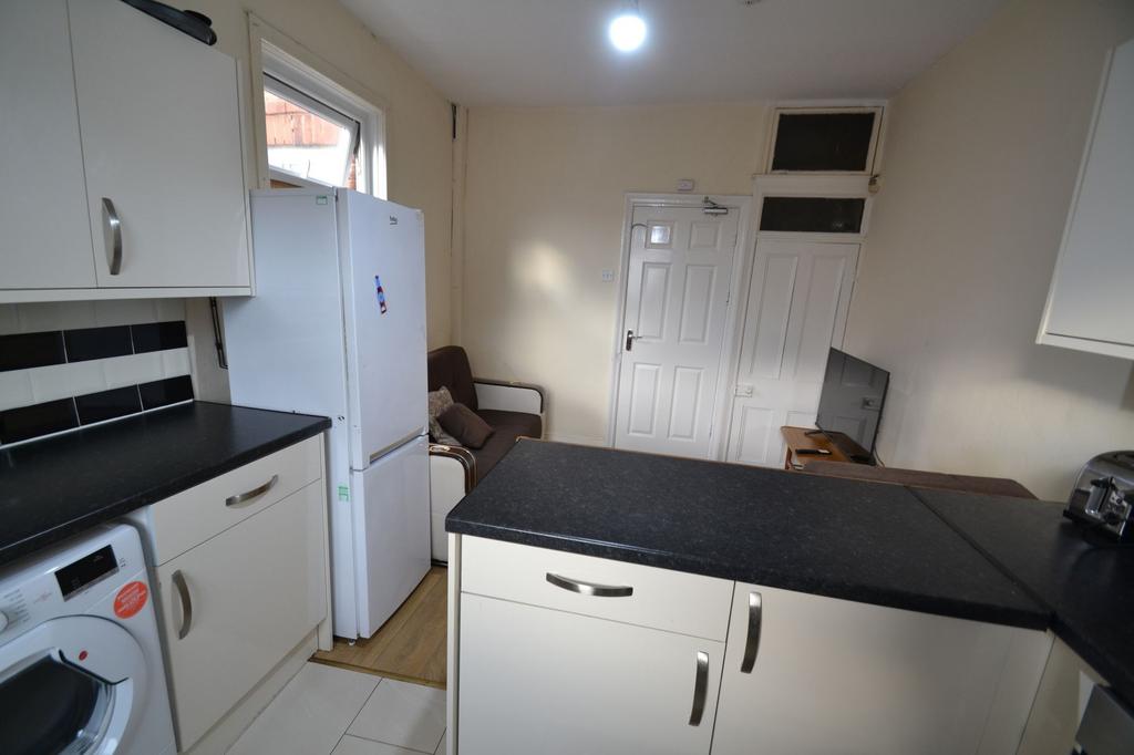 Compact kitchen with modern white cabinets, bla...