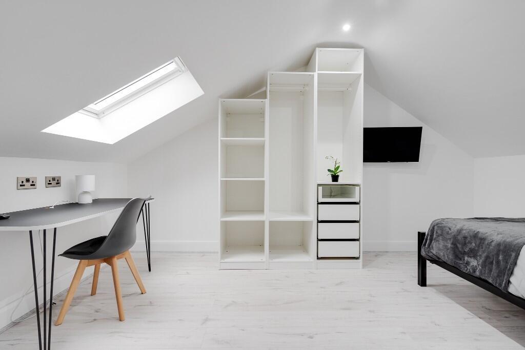 Bright, modern attic bedroom with clean white d...