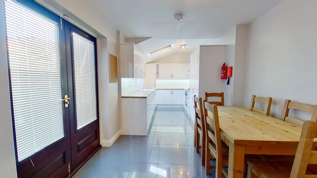 Bright modern galley kitchen and dining area wi...