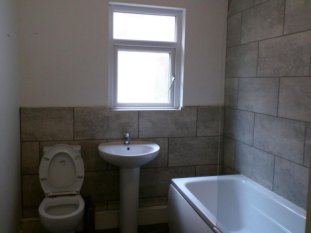 Bright tiled bathroom with a white pedestal sin...