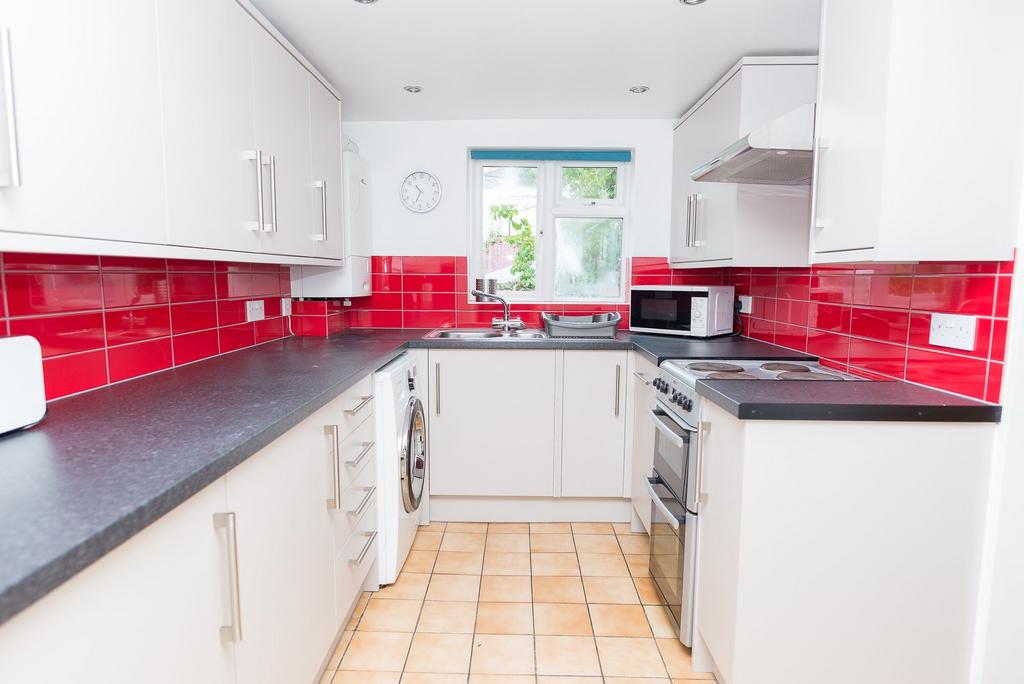Bright modern galley kitchen with glossy red ti...