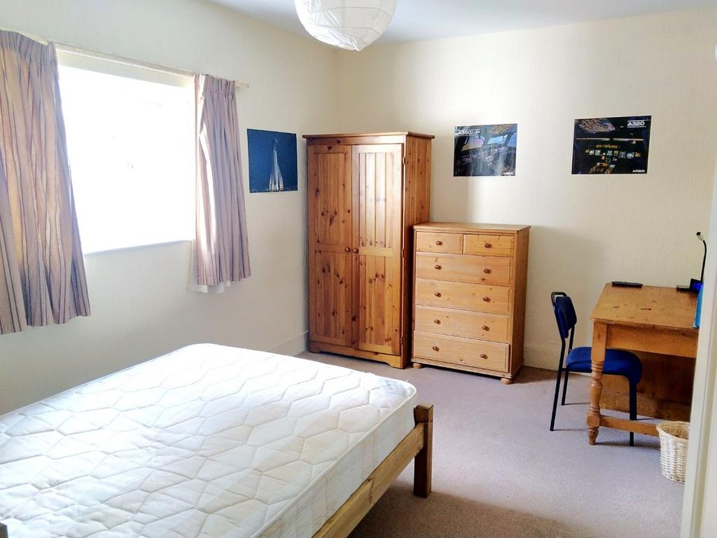 Bright, tidy bedroom with a large window, woode...