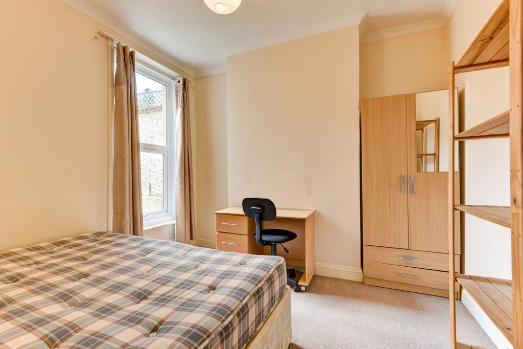 A well-lit, cozy single bedroom with a large wi...