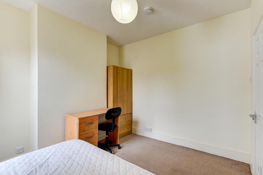A tidy bedroom featuring a desk and wardrobe, w...