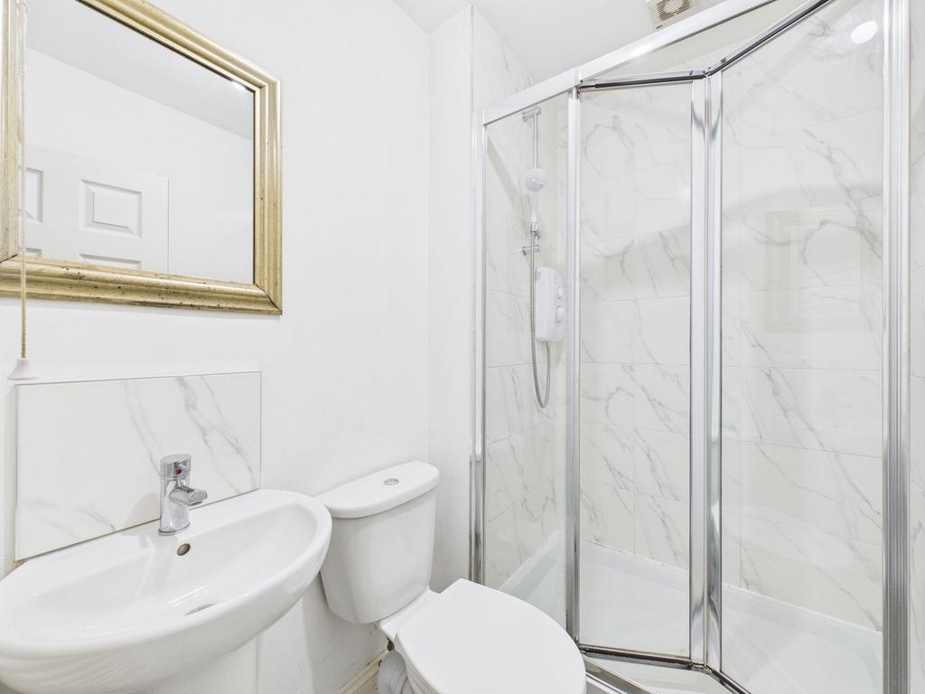A modern, clean bathroom featuring a corner sho...