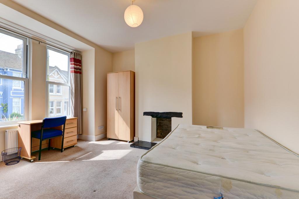 A bright and tidy bedroom featuring a large win...