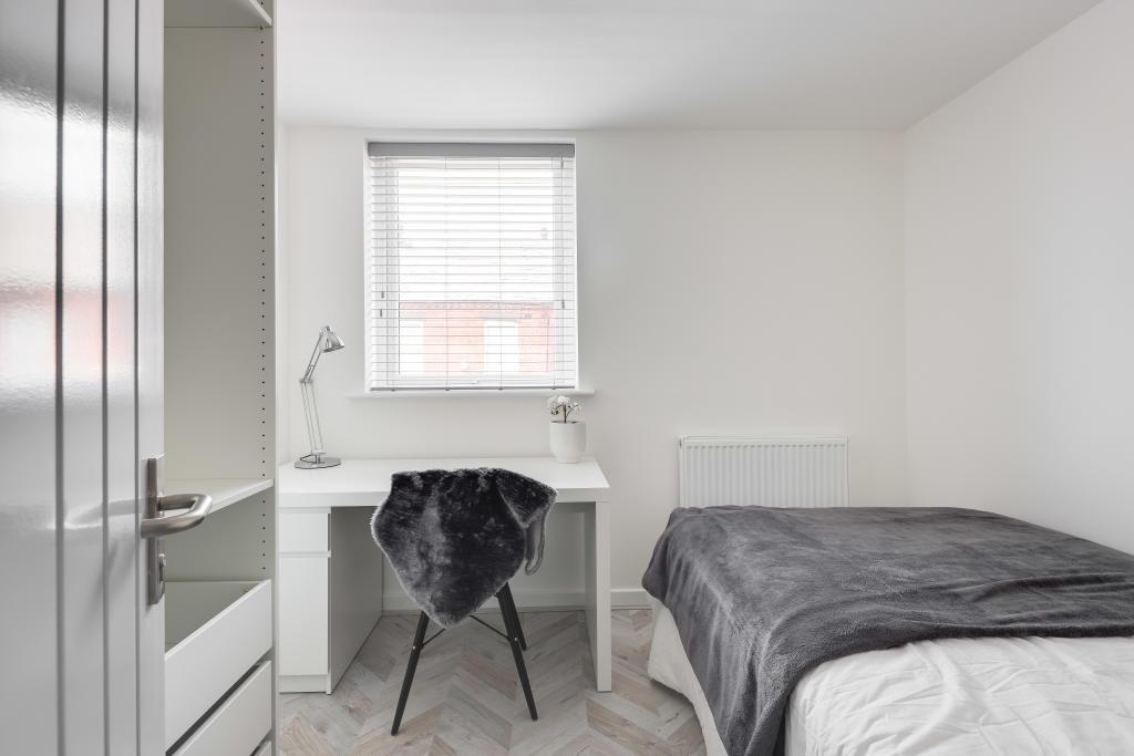 A bright and tidy bedroom featuring a neatly ma...