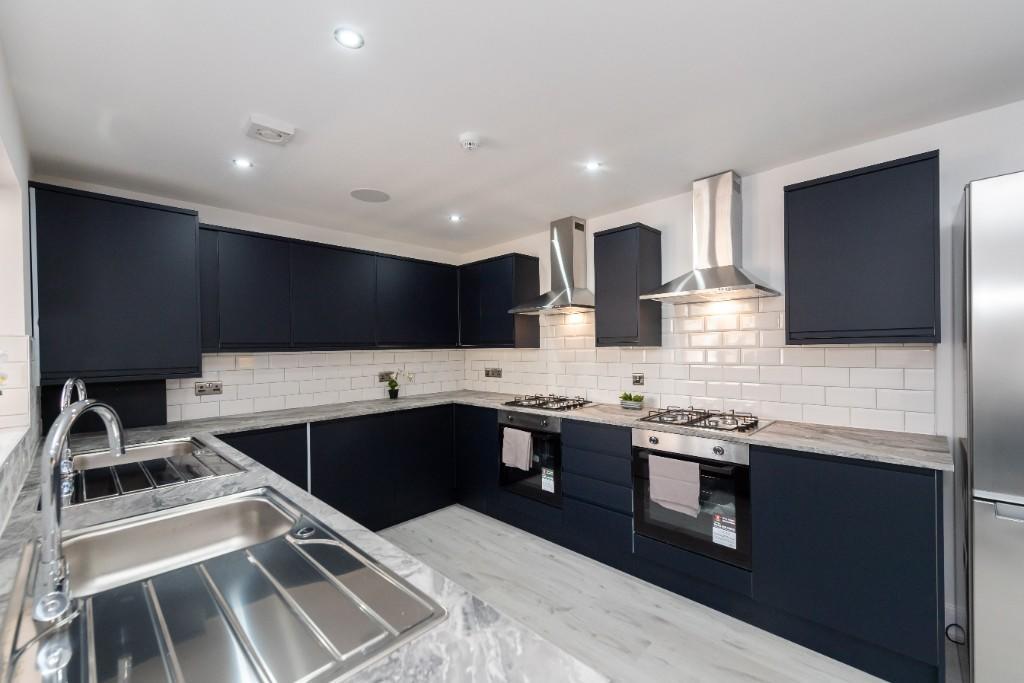 Modern fitted kitchen with deep navy cabinets, ...